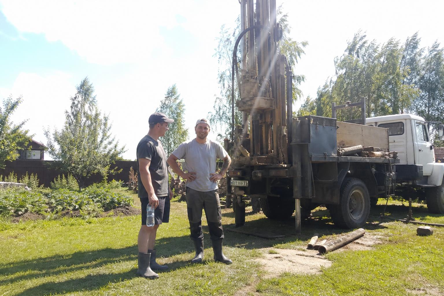 Бригада из двух человек у буровой установки на участке