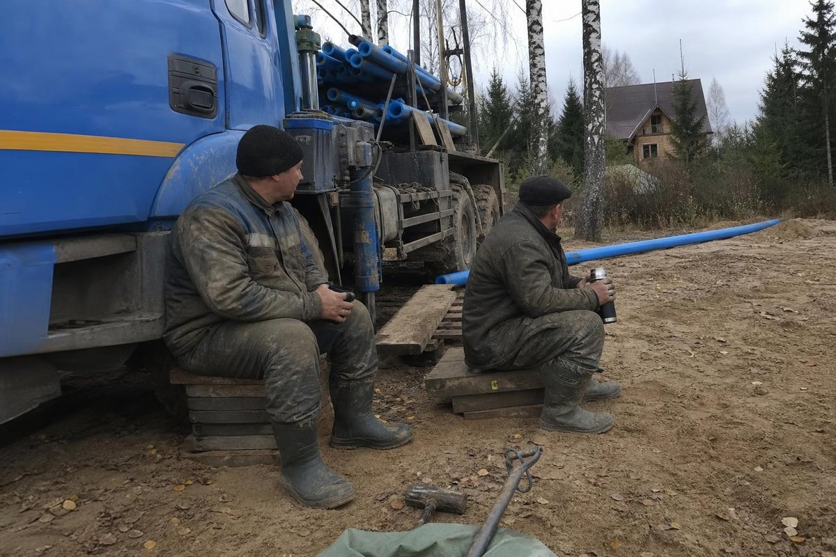 Двое рабочих на коротком перерыве у буровой установки, термос